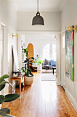 Houseplants in a wide hallway with wooden floorboards, view of the living room