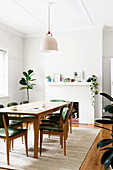 Table and chairs in front of fireplace and houseplant in white dining room