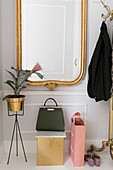 Gilt-framed mirror, plant stand, handbag and brass coat stand in white hallway