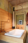 Bathtub and shower with copper fittings in wood-panelled bathroom