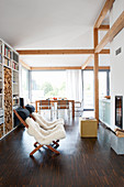Fur blankets on loungers in front of fireplace in open-plan interior