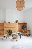Vintage rattan chairs, table and serving trolley in front of half-height wardrobe with open front