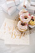 Donuts with pink icing decorated with pink sprinkles and gold leaf