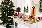 Desserttisch mit warmen Apfelpunsch, Gugelhupf und Dripping Cake, im Hintergrund Weihnachtsbaum