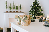 Weihnachtliche Geschenktüten aus braunem Papier auf weißem Tisch