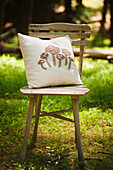 Mushroom-patterned cushion on chair in sunny woodland clearing