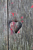 Heart-shaped pastry cutter on wooden surface splattered with red paint