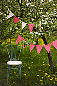 Delicate chair below bunting hung from flowering cherry tree