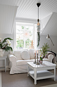 White loose-covered sofa in white room with dormer window and Christmas decorations