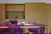 Esstisch mit Stühlen in Violett vor der Küchenzeile mit Schiebetüren