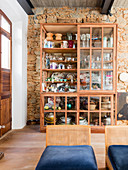 Crockery in rustic glass-fronted cabinet against stone wall