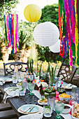 Lanterns above table set in bright colours for Mexican party