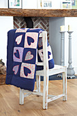 Heart-patterned quilt hung over chair backrest
