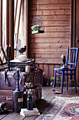 Vintage Vogelkäfig, blauer Stuhl, ausgestopfte Vögel und Koffersammlung im Zimmer mit Holzwand