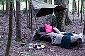 Cushions and blankets on vintage camping bed in woods