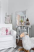 White loose-covered armchair, console table against mirror and rocking sheep