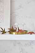 Two mushroom ornaments and autumn leaves on golden tray