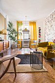 Mustard-yellow sofa, table and chairs below window and potted palm in living room