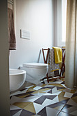 Towel rack, toilet and bidet in bathroom with tiled floor