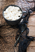 Heisses Getränk mit Marshmallows in schwarzer Tasse auf schwarzem Netz