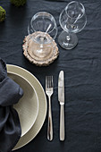 Gedeckter Tisch mit dunkler Tischwäsche, beigefarbenem Geschirr und Baumscheibe als Glasuntersetzer