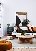 Wooden coffee table, sofa with brunette woman, house plants and picture on sideboard in living room