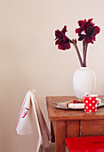 Deep red amaryllis in white vase on wooden table