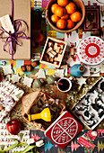 Pastry cutters, gifts, stamps, tangerines, biscuit tin and mulled wine jumbled on table