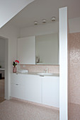 Simple white cabinets and washstand in bathroom with mosaic tiles