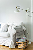 Basket of magazines and standard lamp next to sofa