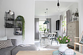 Grey sofa and wire shelving in bright living room with dining area in background