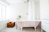 Pink free-standing bathtub in white bathroom