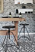 Rustic wooden table and black stools in kitchen with black-and-white patterned floor tiles