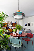 Round table, houseplants and chairs in open-plan interior