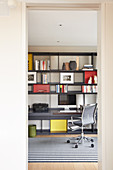 Fitted shelving with integrated desks and office chairs in study