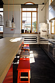 Kücheninsel mit Barhockern in umgebautem Loft mit Rundbogenfenster