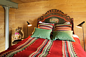 Double bed with ethnic accessories in wood-panelled bedroom