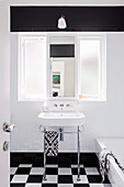 Pedestal sink under interior window in black and white bathroom
