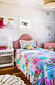 Bed with colorful patchwork blanket in girl's room