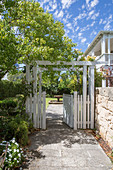 White painted wooden gate next to a low natural stone wall
