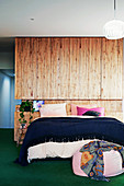 Double bed in front of room divider with wooden paneling