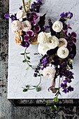 Dramatic table arrangements in white and violet on a marble table