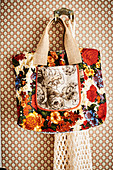 Floral shopping bag hung on hook on patterned wallpaper