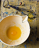 Egg yolk in vintage bowl and whisk