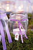 Advent calendar made from tealights jars in moss wreath