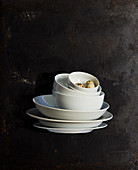 Quail eggs in stacked white bowls and plates against black background