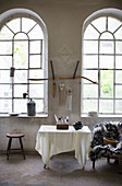 White cloth on table in front of large arched windows