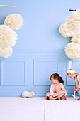 Two girls with a bunny in the room with light blue wall
