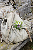 Tiny posy of wildflowers on walker's knapsack on wooden bench