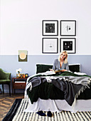 Young woman with book in bed, framed artwork on wall